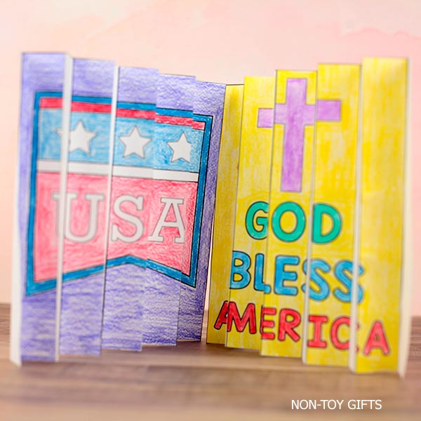 Patriotic Christian craft printable with “God Bless America” agamograph design, coloring activity, and faith-based writing prompts for elementary students.